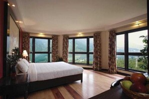 A bedroom with a large bed, multiple windows, and a view of the outdoors.