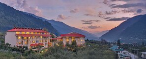 A hotel with multiple buildings, red roofs, and a mountainous backdrop.