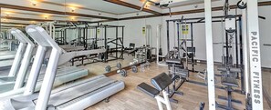 A gym with treadmills, weight machines, and a mirrored wall.