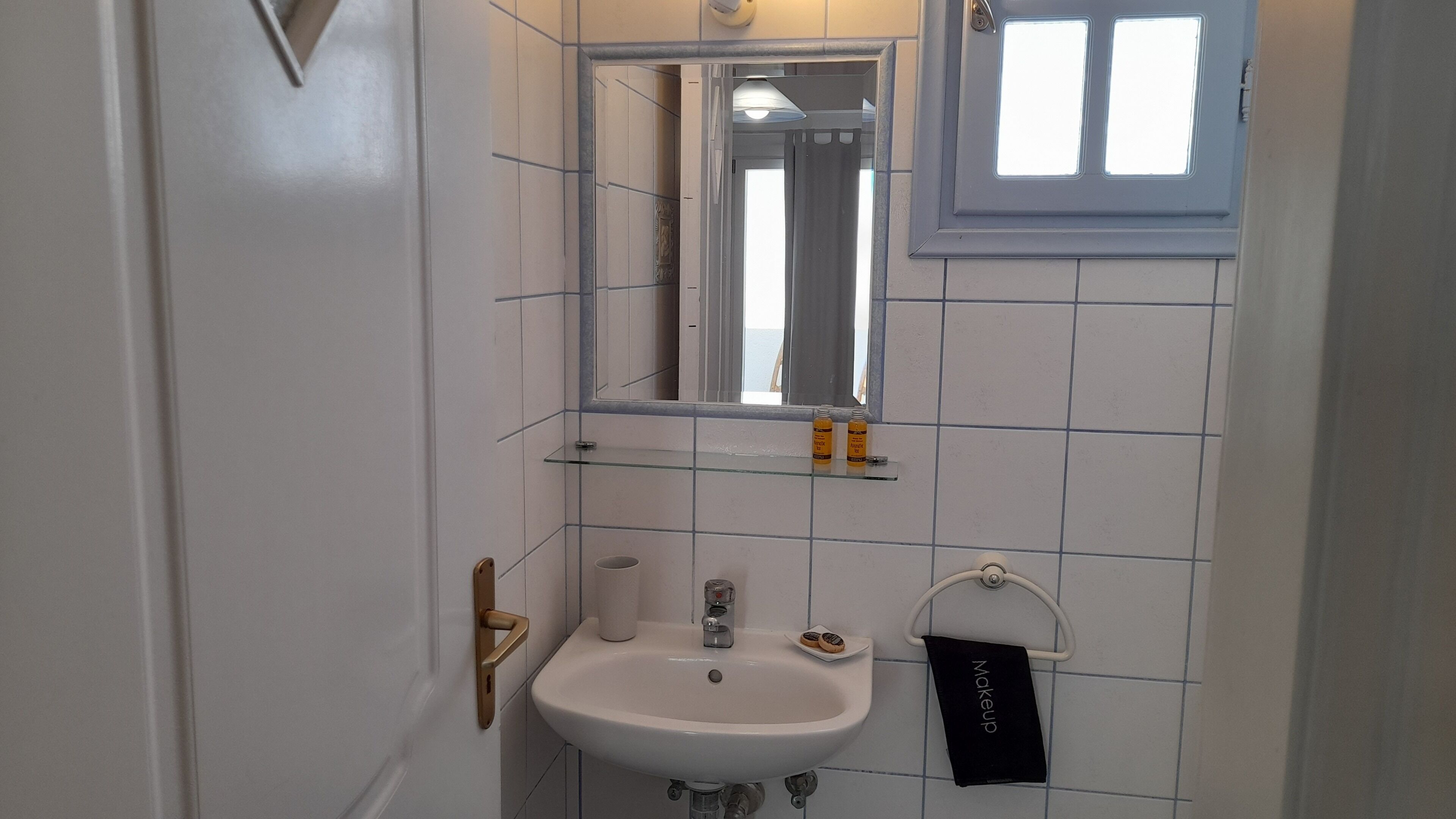 A bathroom with a white sink, a mirror, a towel rack, and a window.