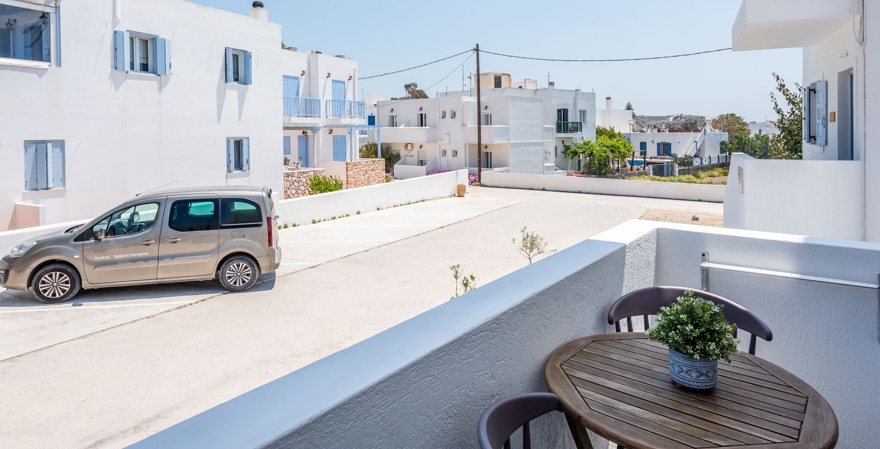 A beige car parked on a street with white buildings in the background.