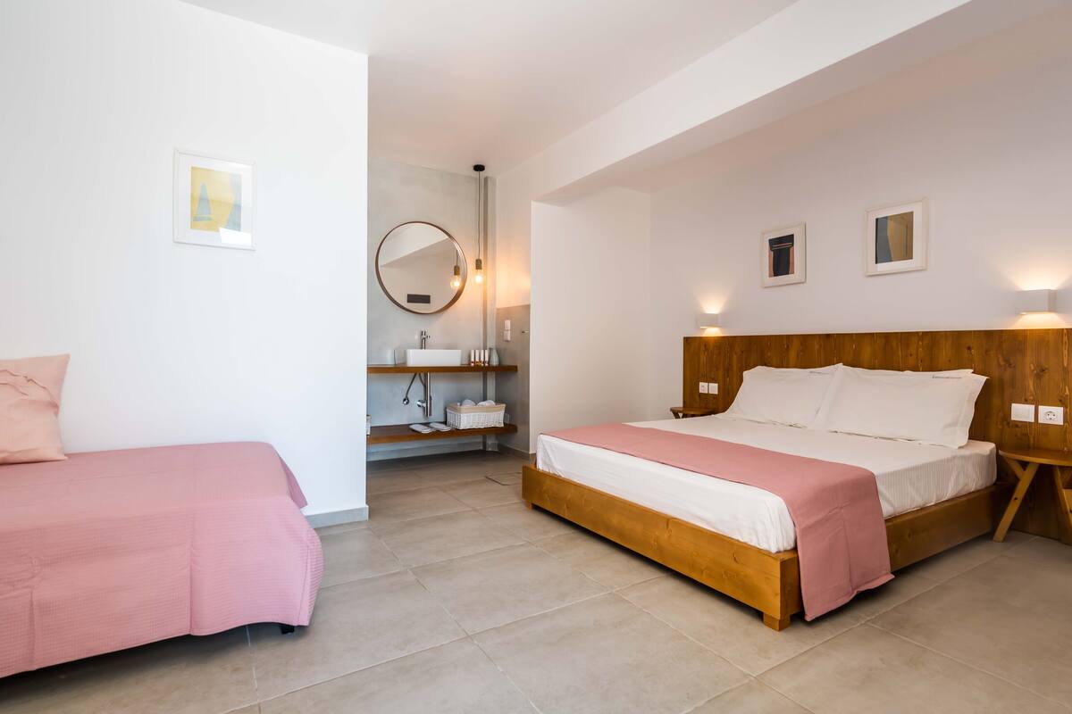 Quarto com duas camas, cabeceira de madeira, mesa de cabeceira, espelho e prateleira com cesta.