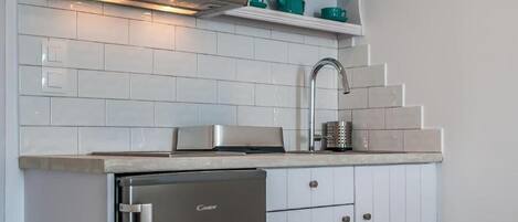 Een moderne keuken met witte kasten, een roestvrijstalen koelkast en een inbouwoven.