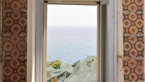 A window with a view of the sea, surrounded by patterned tiles.