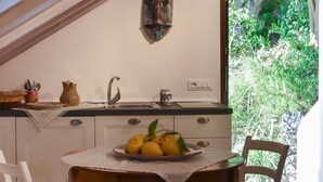 A kitchen with a wooden table, a sink, and a window overlooking greenery.