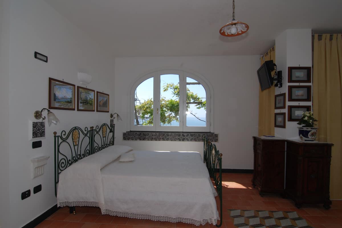 A bedroom with a bed, a window, a dresser, and wall decorations.