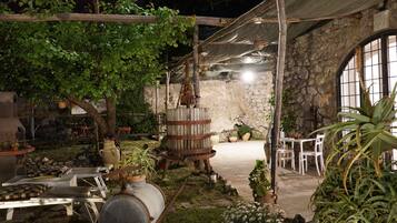 An outdoor patio with stone walls, wooden furniture, and potted plants.