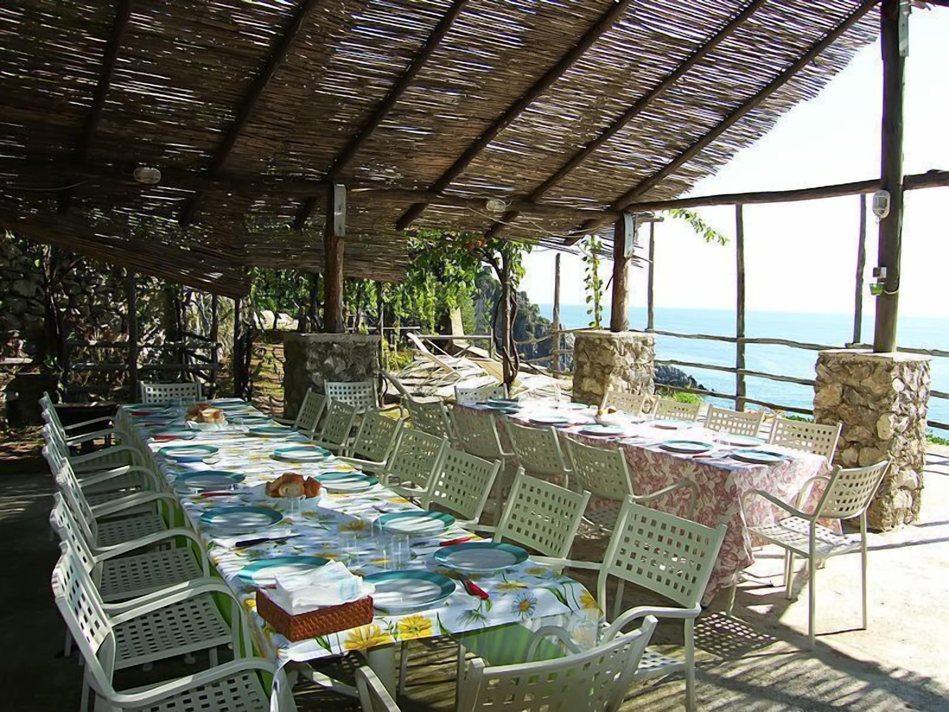 An outdoor dining area with tables set for a meal, overlooking a scenic view.
