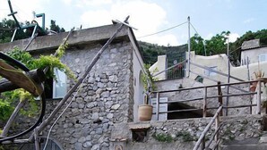 A stone staircase leading to a rustic stone building with a small garden area and potted plants.