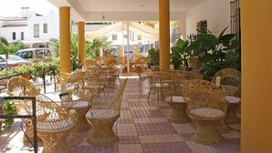 Un espace extérieur aménagé avec des meubles en osier et des plantes en pot.