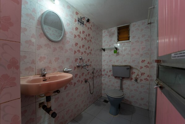 Un baño con lavamanos rosa, inodoro y ducha.