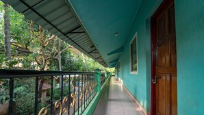 A corridor with a green wall, a wooden door, and a metal railing. - Nelmar Nest Guest House (Calangute)