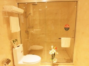 Un baño con ducha envuelta en vidrio, inodoro y lavabo.