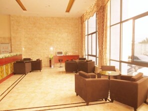 Un vestíbulo con mostrador de recepción, zona de estar y ventanas amplias.