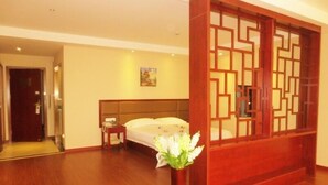 Ein Hotelzimmer mit Holzboden, einem Bett mit weißer Bettwäsche, einem Nachttisch mit Telefon und einem dekorativen Holzverkleidungselement.