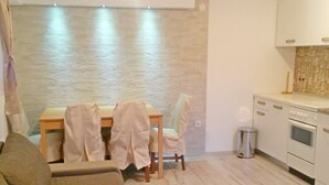 A modern kitchen with a dining area, a sofa, and a trash bin. - House Josipa (Plitvicka jezera)