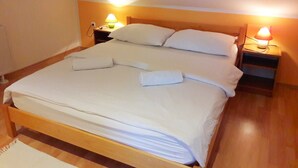 A neatly made bed with white linens and pillows, two bedside lamps, and a wooden headboard. - House Josipa (Plitvicka jezera)