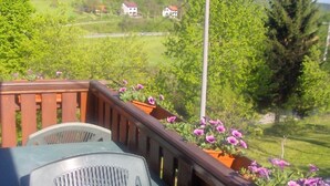 A balcony with a table and chairs, wooden railings, and flower planters. - House Josipa (Plitvicka jezera)
