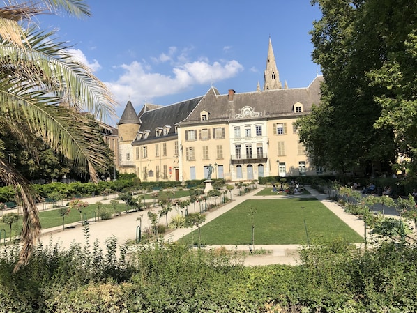 A historic building with a central courtyard, surrounded by lush greenery and a well-maintained lawn.