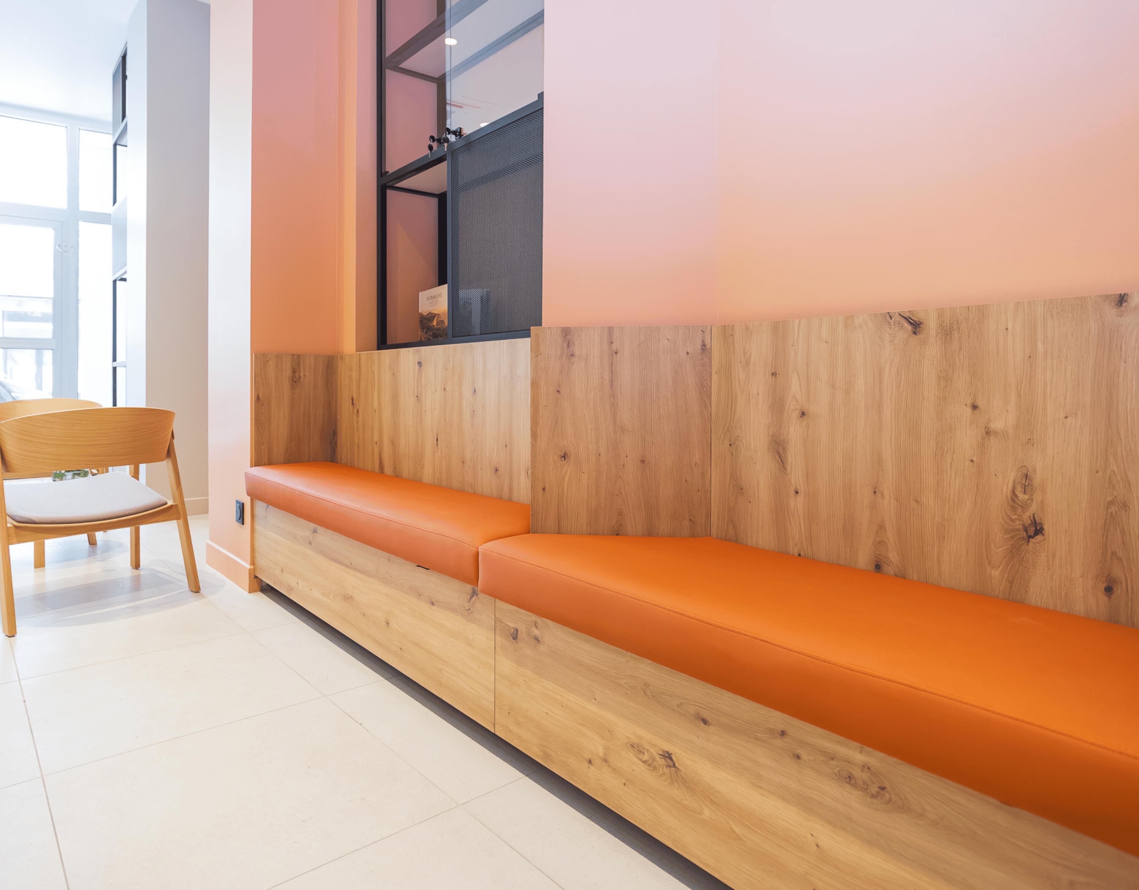 A modern interior with a wooden bench, a chair, and a glass partition.
