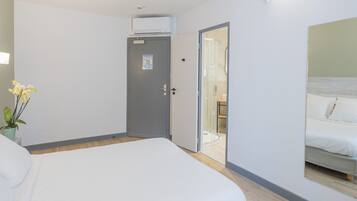 A hotel room with a bed, a door leading to a bathroom, and a large mirror on the wall.