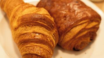 Un plato con dos croissants y un tazón pequeño de comida.