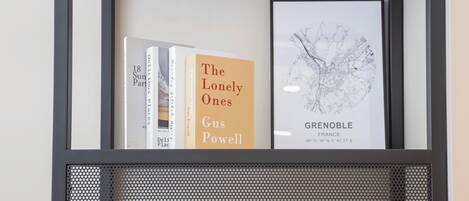 A framed book display with 'The Lonely Ones' by Gus Powell and a map of Grenoble, France.