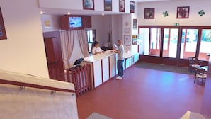 Un área de recepción con mostrador, un televisor montado encima y vistas al exterior a través de amplias ventanas.