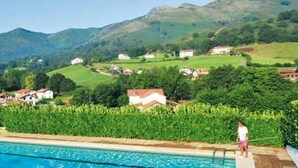 Una piscina con vistas a casas y montañas al fondo.
