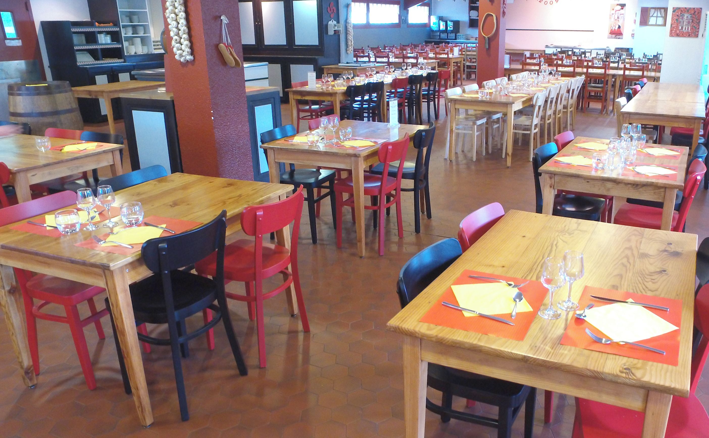 Un restaurante con varias mesas y sillas, algunas con menús y vasos colocados.