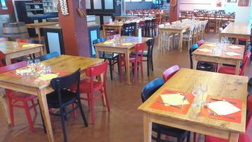 Un restaurante con varias mesas y sillas, algunas con menús y vasos colocados.