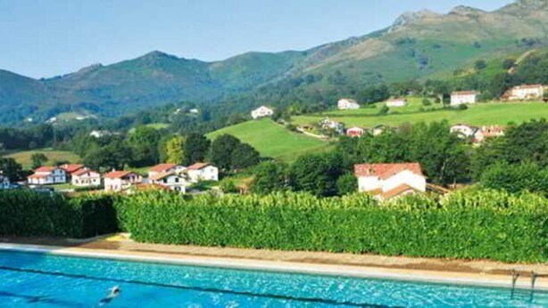 Una piscina con vista a casas y montañas al fondo.