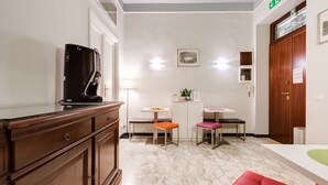 A compact kitchen with a built-in microwave, a small dining area with two stools, and a wooden cabinet. - B&B 2 Passi Al Colosseo (Rome)