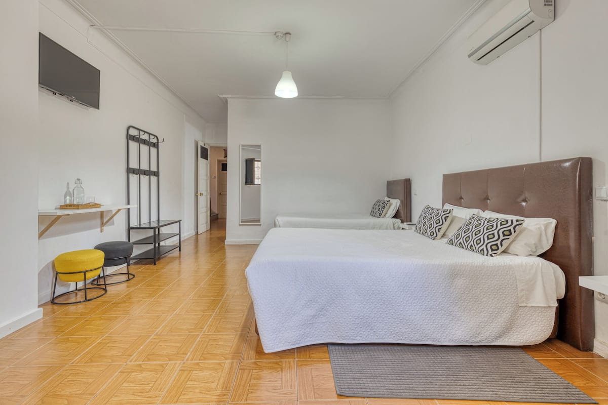 A bedroom with a large bed, a desk, two chairs, and a hanging light fixture.