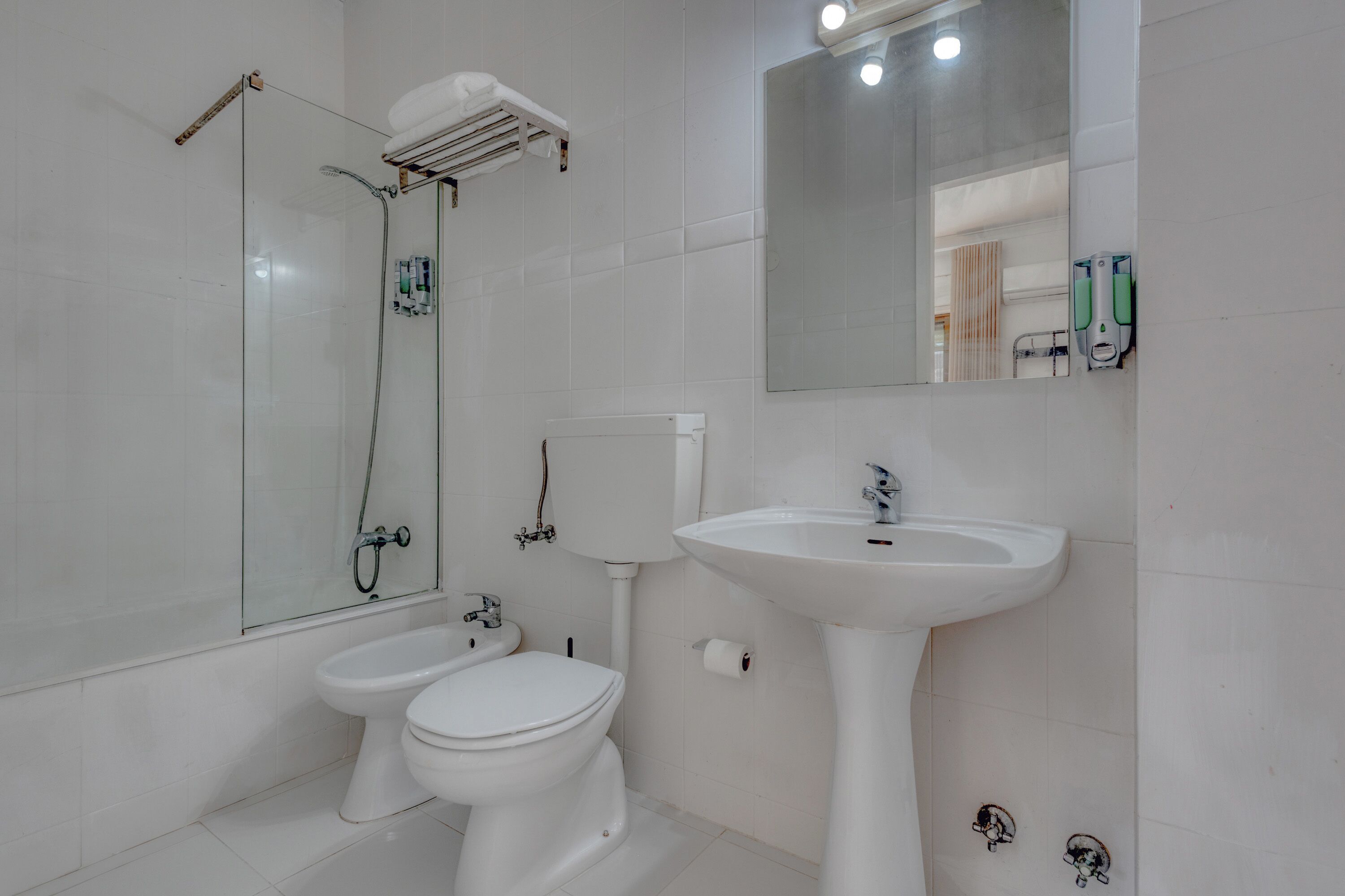 Un baño moderno con cabina de ducha de vidrio, lavabo pedestal y inodoro.