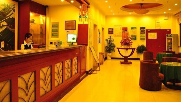 A hotel lobby with a reception desk, a large plant, and a red door. - GreenTree Inn Suzhou Mudu Ancient Street Express Hotel (Suzhou)