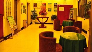 A hotel lobby with a central table, red upholstered chairs, and a green table. - GreenTree Inn Suzhou Mudu Ancient Street Express Hotel (Suzhou)
