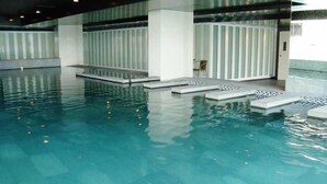 An indoor swimming pool with clear water, white pillars, and a tiled floor. - Bangkok City Hotel (Bangkok)