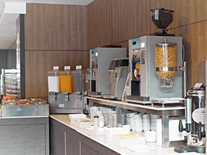 Un espace dédié au café, équipé de plusieurs machines à café, d’un moulin à café et d’une variété de tasses et de soucoupes.