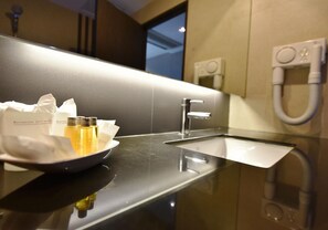 Een hotelbadkamer met een wastafel, spiegel en handdroger.