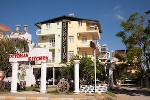 A multi-story building with a sign for 'Nergosside' and 'Ottoman Kitchen' indicating a restaurant. - Naz Garden Side (Manavgat)