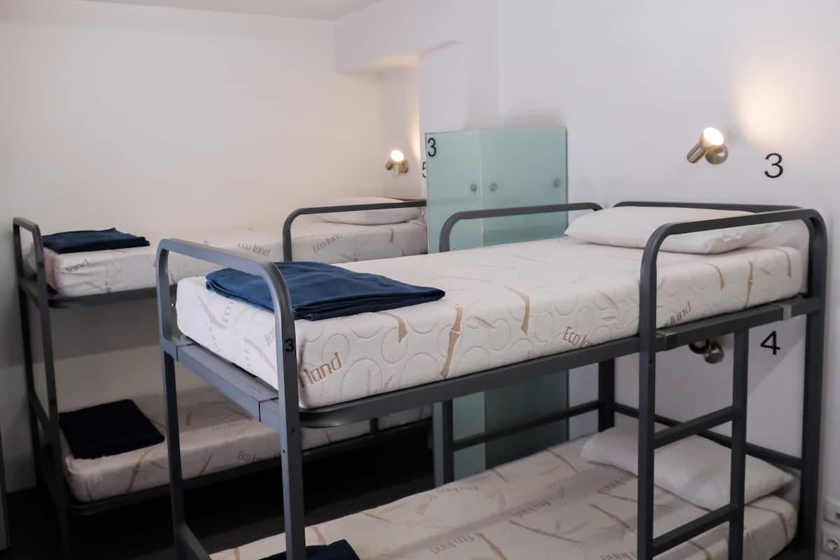 Un dormitorio con literas, un armario y luces fijadas a la pared.