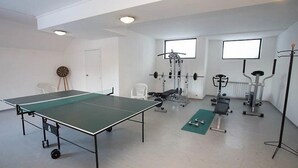 A gym with a ping pong table, weightlifting equipment, and exercise mats. - Laplandia Hotel (Smolyan)
