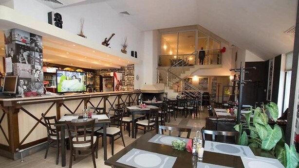 A restaurant with multiple dining areas, a bar, and a staircase leading to an upper level. - Laplandia Hotel (Smolyan)