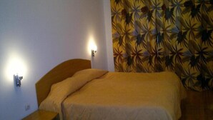 A single bed with a headboard, a bedside table, and a wall-mounted light fixture. - Laplandia Hotel (Smolyan)