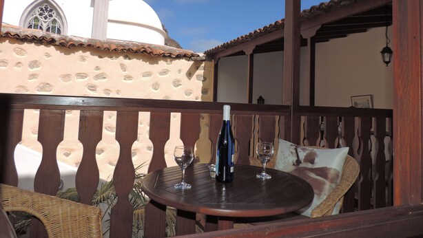 A patio with a round table, two wine glasses, and a bottle of wine. - Casa Los Helechos (Agulo)