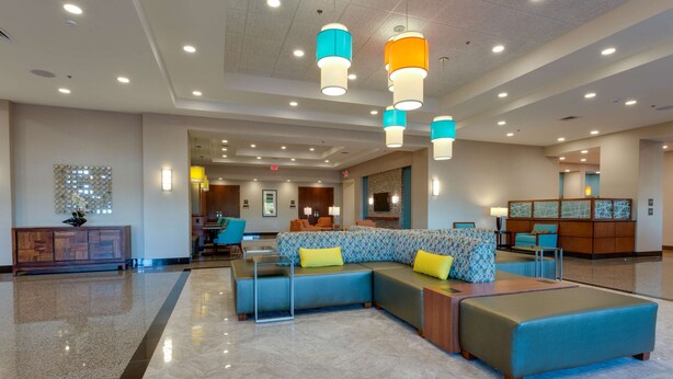 A spacious lobby with a sectional sofa, a wooden cabinet, and a television mounted on the wall. - Drury Inn & Suites Gainesville (Gainesville)