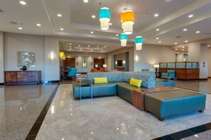 A spacious lobby with a sectional sofa, a wooden cabinet, and a television mounted on the wall. - Drury Inn & Suites Gainesville (Gainesville)