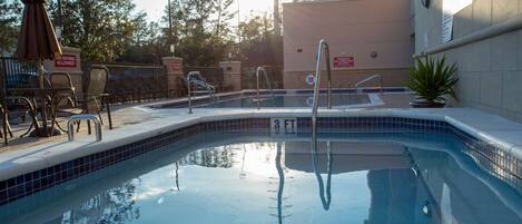 A swimming pool with a tiled edge, a lifebuoy, and a sign indicating no diving allowed.
