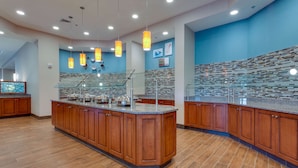 A modern kitchen with wooden cabinets, a granite countertop, and pendant lighting. - Drury Inn & Suites Gainesville (Gainesville)